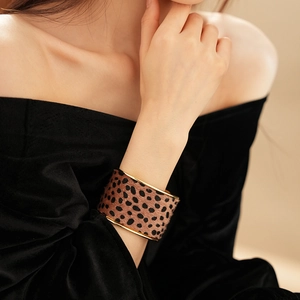 Close-up of leopard print wide cuff bracelet on model with golden metal frame finish
