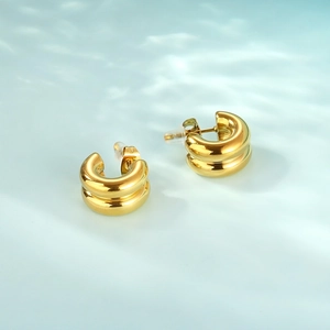 Detail of gold double C-hoop earrings with 18k finish on a blue water ripple background
