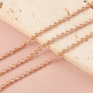 Détail macro d'une chaîne à billes or rose de 2,4 mm avec éclat métallique sur pierre