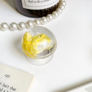 Macro shot of a clear round phone grip featuring a yellow cloud resin design on a desk