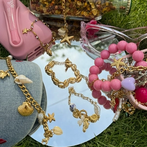 Detail of ocean-themed gold charm bracelet with starfish and shell on a mirror surface