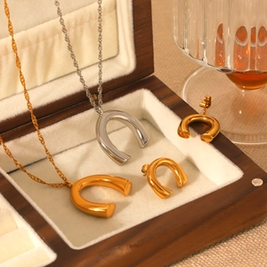 U-shaped pendant necklaces and earrings set in gold and silver finish on a display tray