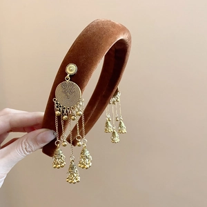 Detailed view of brown velvet headband with ethnic golden bell tassel pendants