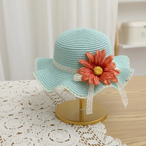 Détail d'un chapeau de paille vert menthe avec décoration florale et ruban en dentelle