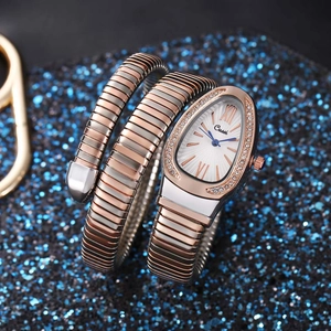 Detail of snake-shaped wrap watch with rose gold and silver band on blue glitter background