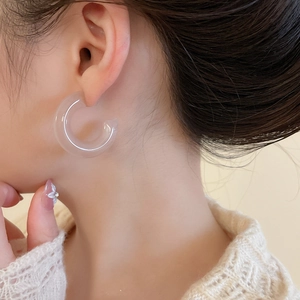 Close-up of translucent acrylic C-shaped hoop earrings worn with a cozy knit sweater