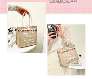 Close-up of linen tote bag with HELLO WEEKEND text and colorful pom pom tassels