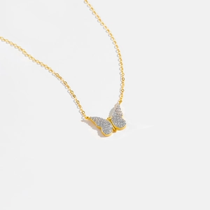Macro detail of a gold butterfly pendant necklace with shimmering white zircon stones