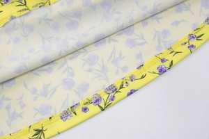 Close-up of overlock stitching detail on floral summer dress with purple flowers