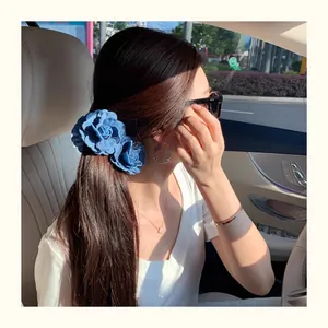 Detailed view of vintage denim blue fabric flower banana hair clip worn on person