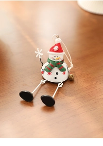 Detail of painted metal snowman figurine with long legs and a bell on wooden surface