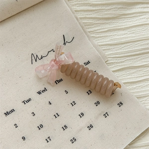 Detail of banana hair clip featuring spiral tube design and elegant ribbon bow