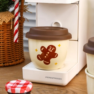 Christmas themed beige ceramic gingerbread man mug with a brown silicone lid and festive decor