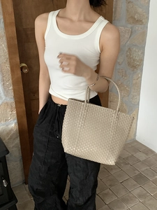 Detailed view of the woven straw tote bag texture and handcrafted beige shoulder strap
