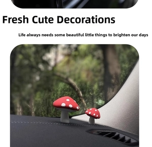 Detail of two red mushroom car ornaments on a dashboard with natural background