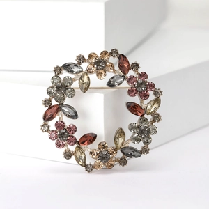 Detail of a floral wreath brooch with colorful rhinestones on a golden metal base