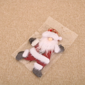 Close-up of plush Santa Claus ornament with red hat and hanging string on burlap surface