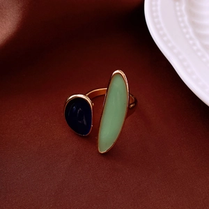 Close-up of a vintage open ring with navy and green resin inlays on a gold-tone band