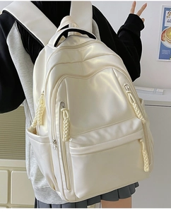 Minimalist beige large capacity backpack shown from a side view on a model