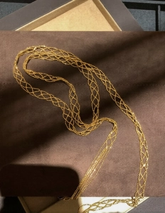 Macro shot of gold woven mesh necklace showing precise diamond grid craftsmanship