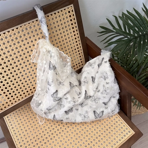 Detailed lace texture of white shoulder bag with butterfly prints and bow strap