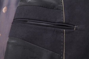 Macro detail of men's navy wool coat featuring inner pocket with golden stitching
