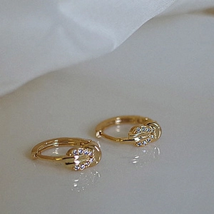 Macro shot of gold leaf-shaped clip-on earrings with shimmering zircon pavé setting