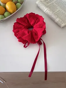Detailed shot of red lace embroidery hair scrunchie with ribbons on a white desktop