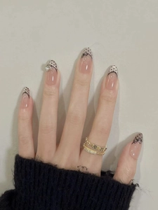 Detail of almond press-on nails with French polka dots, black lace, and heart rhinestone