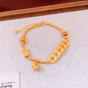 Macro shot of gold-plated beaded bracelet with five-emperor coins and wealth charm