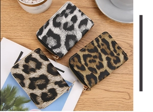 Three compact leopard print accordion card wallets in various colors on a wooden surface