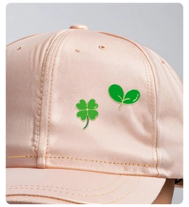 Broches en émail trèfle et jeune pousse sur une casquette en satin rose délicat