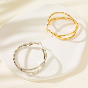 Detailed close-up of double-layered hoop earrings in gold and silver finish on a ceramic tray