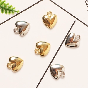 Six gold and silver heart-shaped metal charms for jewelry making on white background
