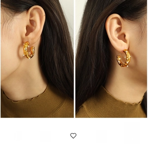 Detail of C-shaped gold-plated hoop earrings with hammered texture and inset pearls