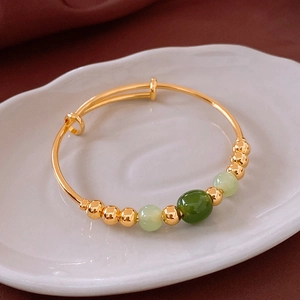 Macro view of adjustable gold-plated bracelet with green jade beads on velvet background