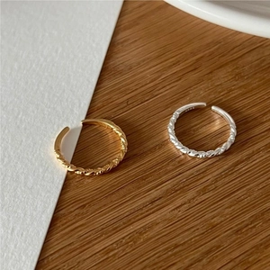 Detail of twisted 925 silver rings in gold and silver finish with adjustable open band