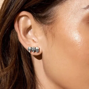 Three-skull punk earrings in silver metal shown on ear for Halloween decoration style