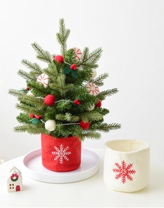 Close-up of a mini Christmas tree in a red felt pot with white snowflake embroidery