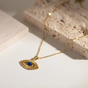 Detail of 18K gold plated evil eye pendant necklace with lapis lazuli on stone blocks