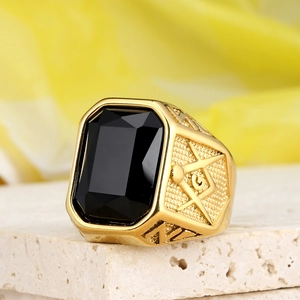 Detailed close-up of a gold Freemason ring featuring a square black gemstone and compass symbol