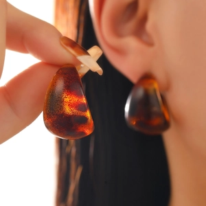Macro view of leopard print amber acrylic earrings showing translucent texture and glossy finish