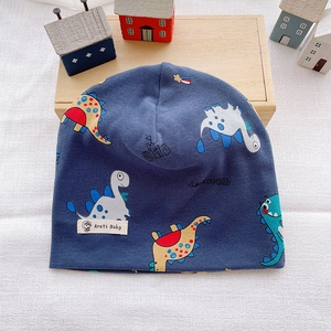 Detail of dark blue baby beanie with colorful dinosaur prints and brand label