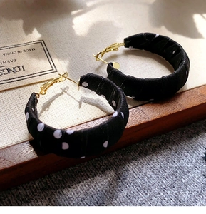 Detail of retro polka dot fabric wrapped hoop earrings with elegant gold metal hooks