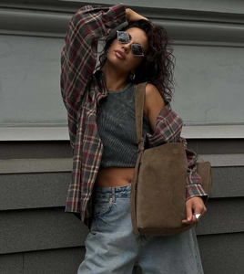 Outdoor street style view of a red plaid shirt paired with a brown suede shoulder bag