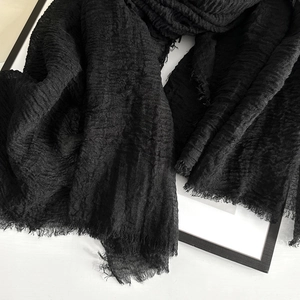 Close-up of black cotton linen scarf with crinkle texture and raw frayed edges