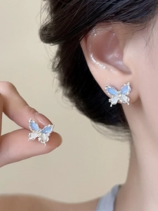 Détail de boucles d'oreilles papillon en argent avec dégradé d'opale bleu et blanc