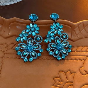 Macro shot of blue crystal flower drop earrings on a vintage textured ceramic plate