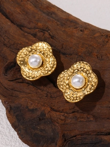 Detail of 18K gold-plated flower stud earrings with pearl on a rustic wood base