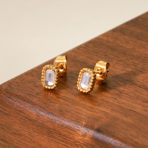 Macro shot of gold stainless steel earrings with square zircon and beaded edge detail